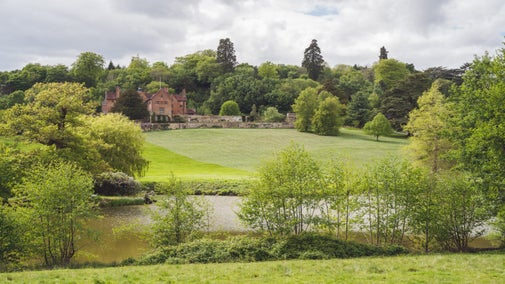 View of Chartwell House from across lake, with lawn in front of house and trees all around
